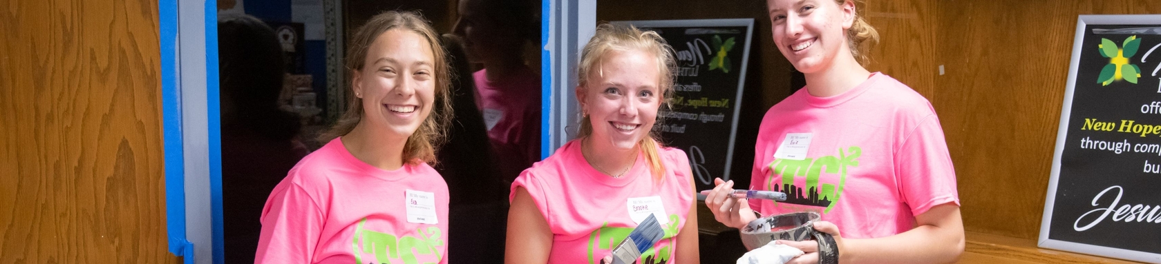 Three teenage girls painting a church as part of a servant event.
