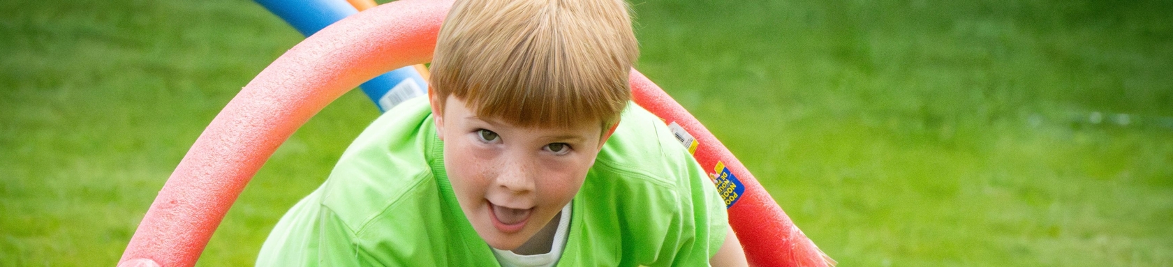 A pre-school boy plays in the grass on the front lawn of the church.