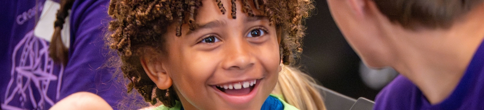 A young boy smiles at a middle school student.