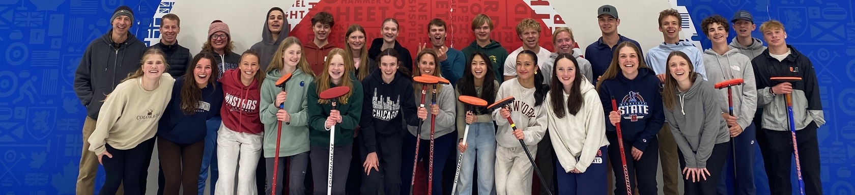 Two dozen youth group members and leaders posing for a group photo at a curling center