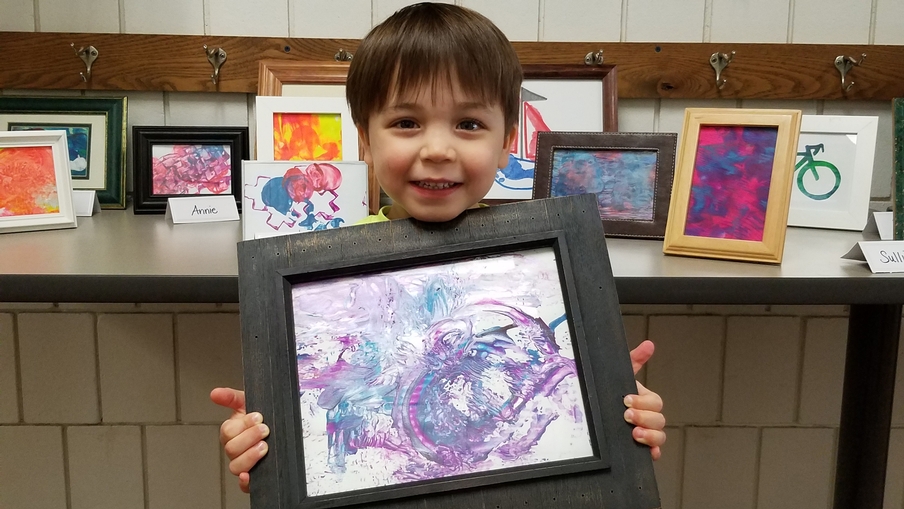 A young ECC boy holds his painting