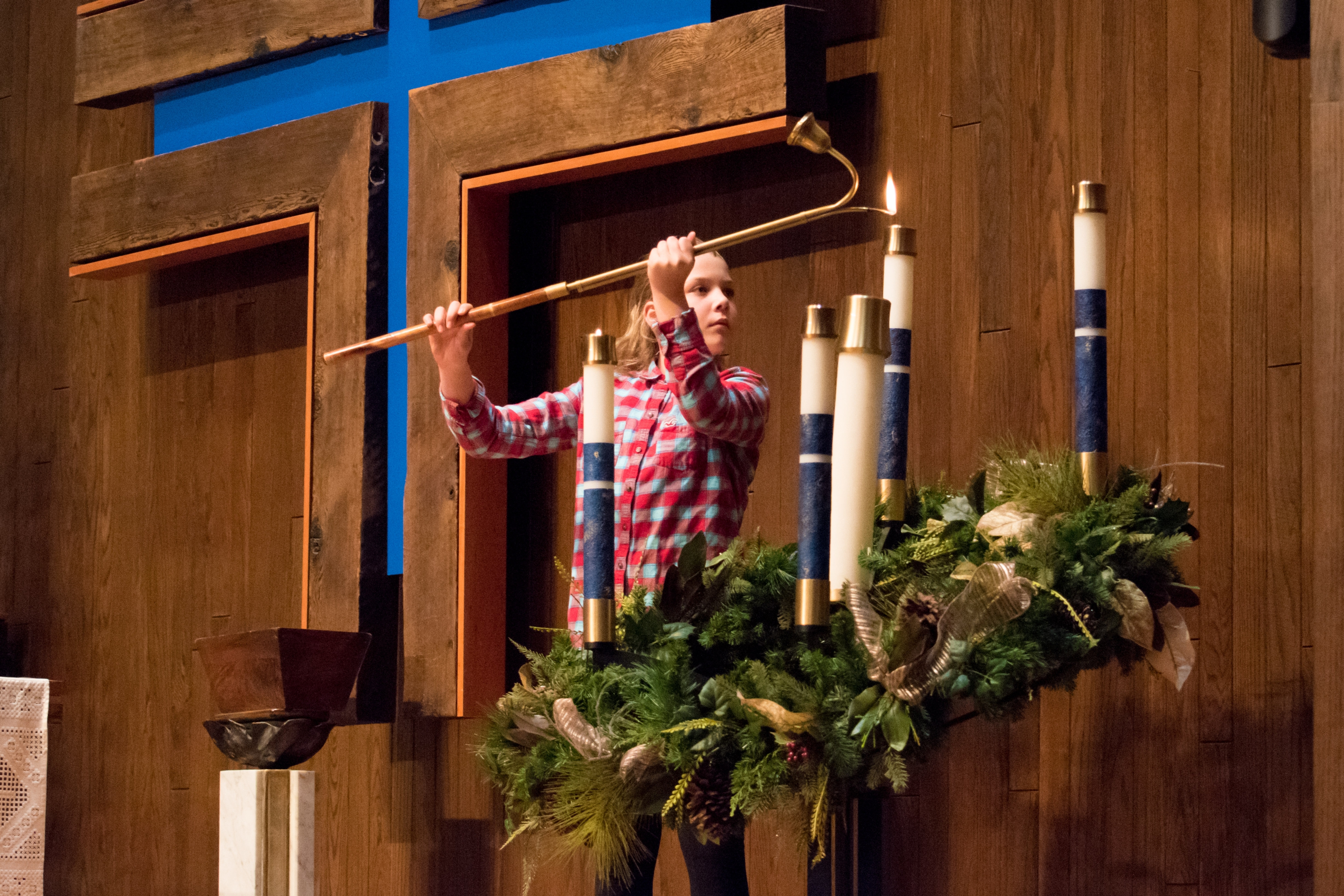 A young girl lights candles on the advent wreath.