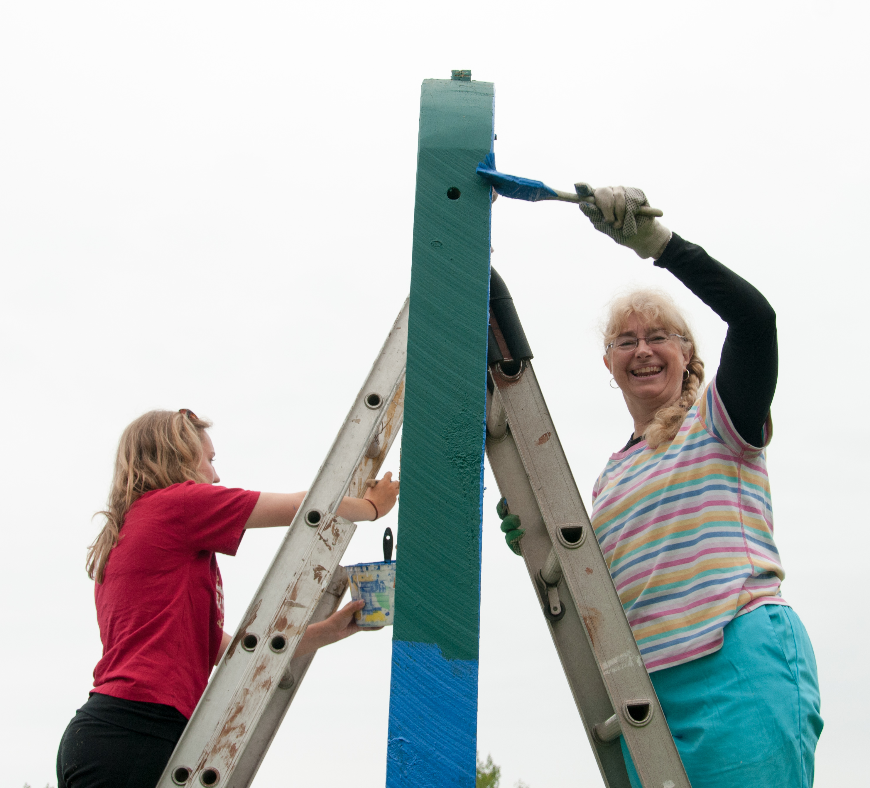 Two women paint a building on a mission trip in Grand Marais